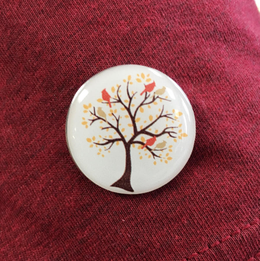 Cardinal Living pin with tree and branches, leaves, and birds in the tree.